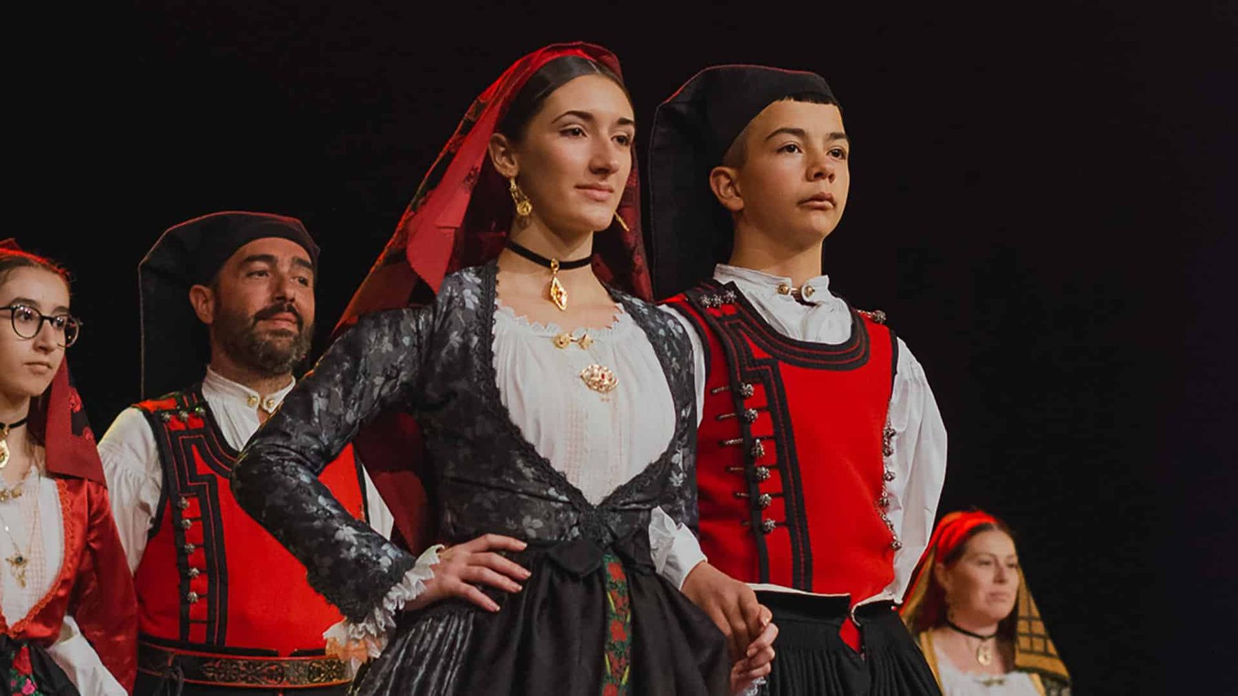 Young people and adults in traditional Sardinian dress during a folk parade in Ogliastra