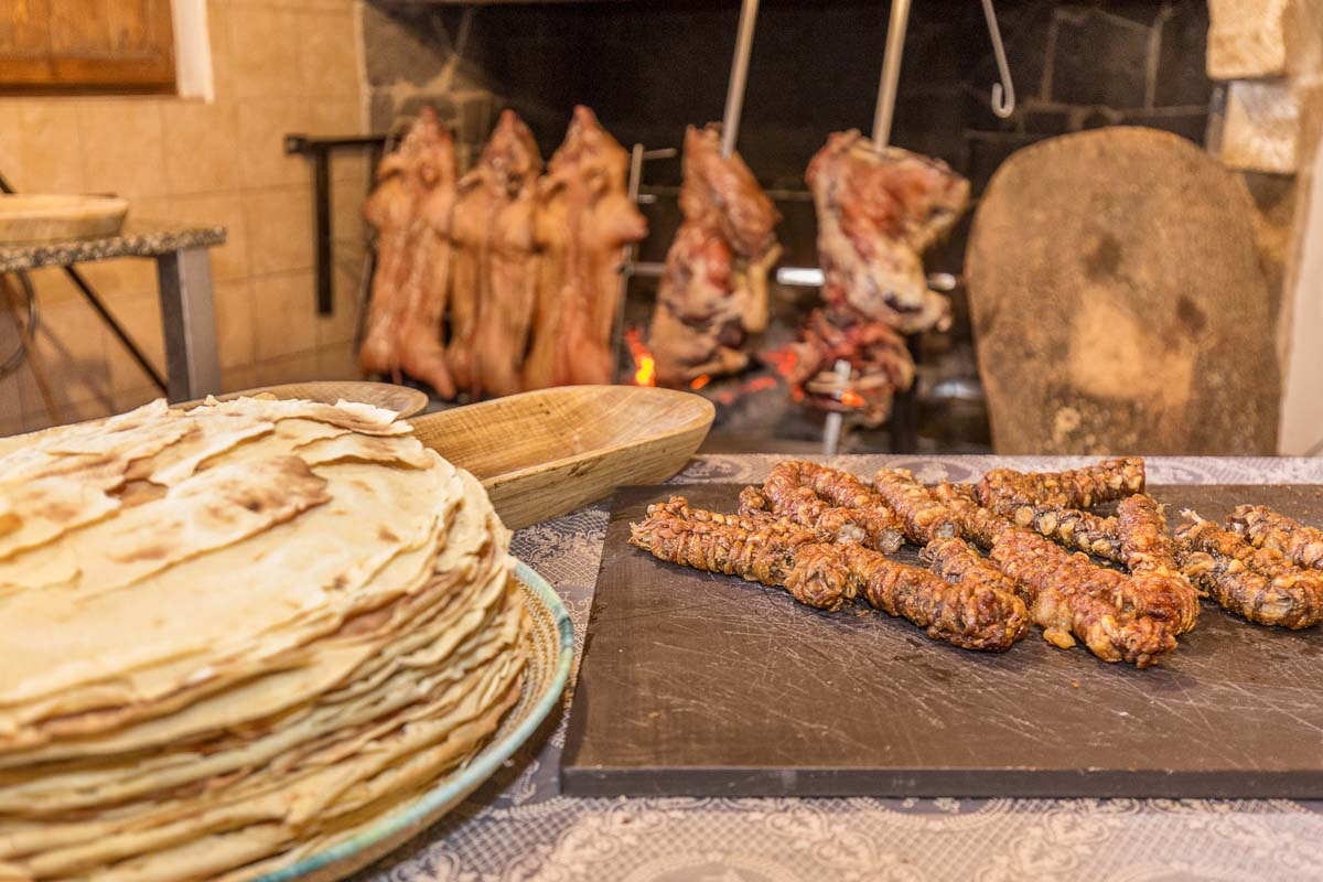 Pane carasau e arrosto allo spiedo davanti al camino di un agriturismo dell'Ogliastra
