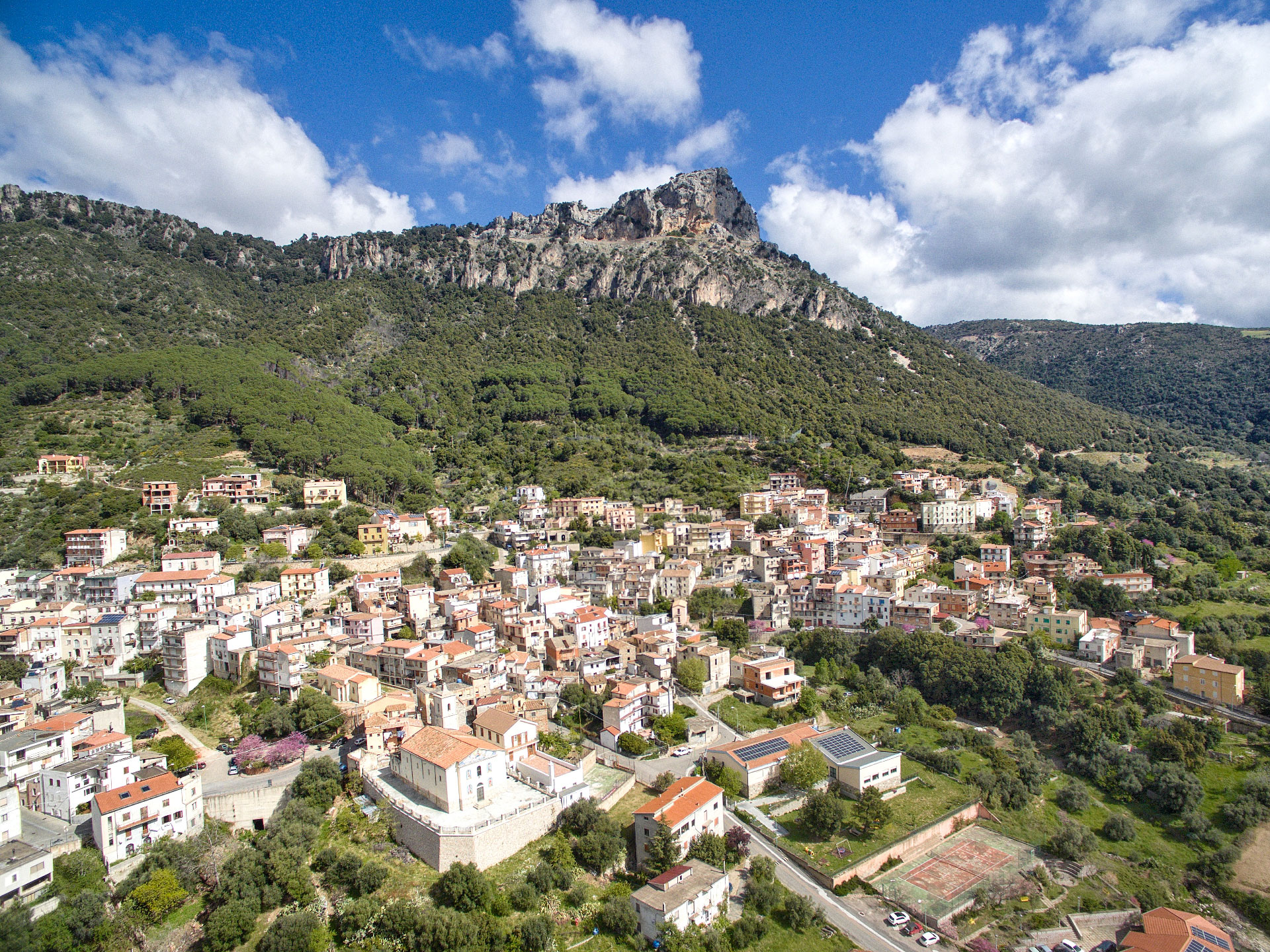 Aerial view of the village of Urzulei with its red-roofed houses at the foot of the mountain